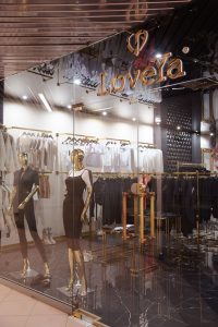 Wnętrze butiku LoveYa z eleganckim wystrojem – marmurowa podłoga, złote lustra, huśtawka ozdobiona kwiatami, oraz ubrania na wieszakach