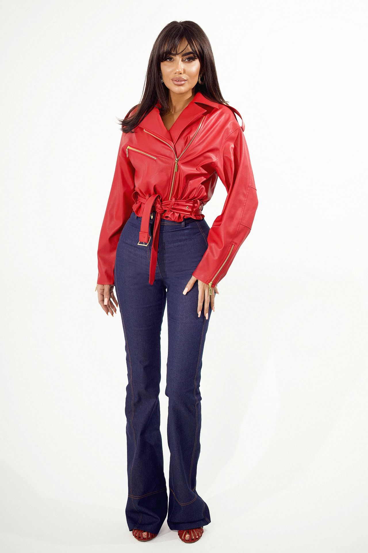 Modelka w czerwonej ramonesce damskiej LoveYa Silvia z paskiem w talii i złotymi zamkami, zestawiona z ciemnymi jeansami, na jasnym tle